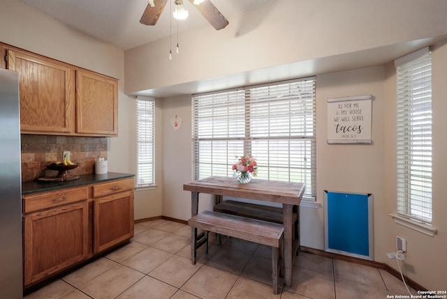 kitchen featuring ceiling fan, light tile patterned floors, a textured ceiling, backsplash, and stainless steel refrigerator