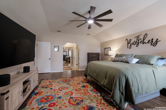 bedroom featuring a textured ceiling, lofted ceiling, dark hardwood / wood-style floors, and ceiling fan