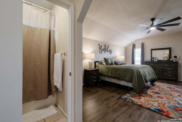 bedroom with a textured ceiling, vaulted ceiling, dark hardwood / wood-style floors, and ceiling fan