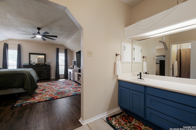 bathroom with a wealth of natural light, lofted ceiling, a textured ceiling, and hardwood / wood-style flooring