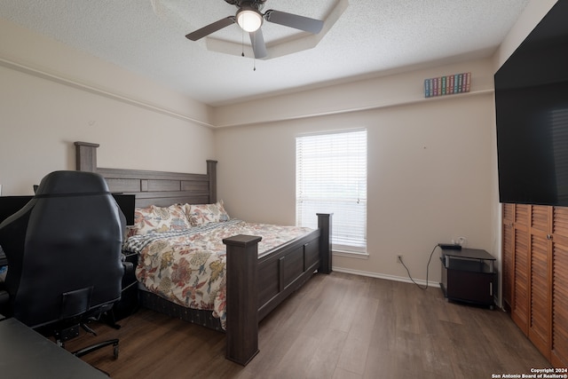 bedroom featuring ceiling fan, hardwood / wood-style flooring, and a textured ceiling