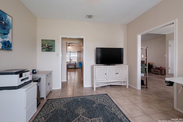 interior space with a textured ceiling, ceiling fan, light tile patterned floors, and white cabinets