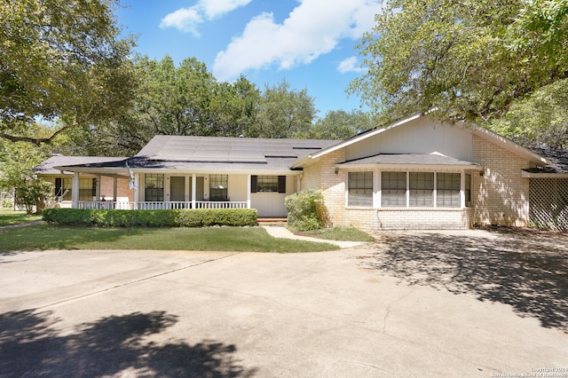 ranch-style house with covered porch and solar panels