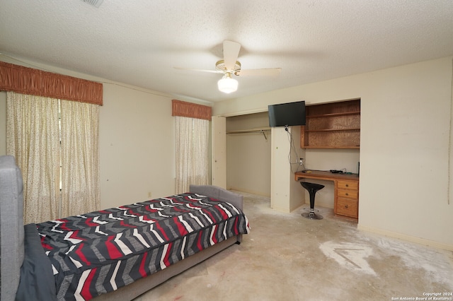 bedroom with a textured ceiling, built in desk, a closet, and ceiling fan