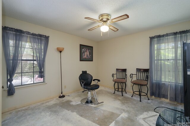 living area featuring ceiling fan and a textured ceiling