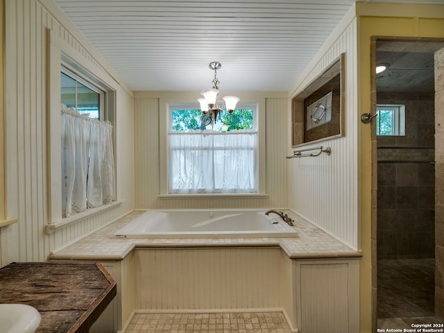 bathroom featuring tile floors, a bathtub, and a chandelier