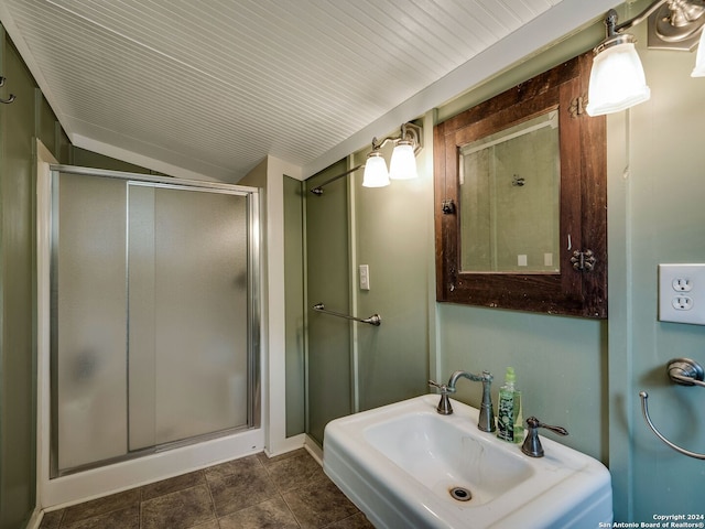 bathroom with walk in shower, vaulted ceiling, sink, and tile flooring