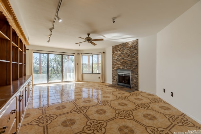 unfurnished living room featuring rail lighting, a fireplace, ceiling fan, and light tile floors