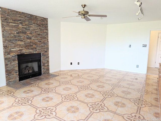 unfurnished living room with light tile flooring, ceiling fan, rail lighting, and a fireplace