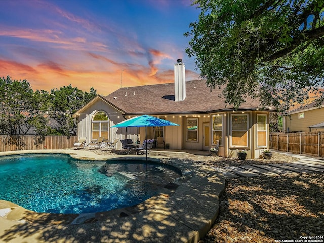 pool at dusk featuring a patio