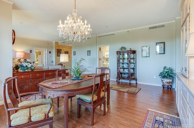 dining room with ornamental molding, a notable chandelier, a textured ceiling, and dark hardwood / wood-style flooring