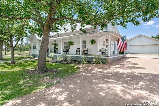 view of front of home with an outbuilding, a porch, a garage, and a front lawn