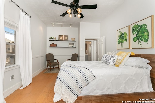 bedroom with ceiling fan, light hardwood / wood-style flooring, and a textured ceiling