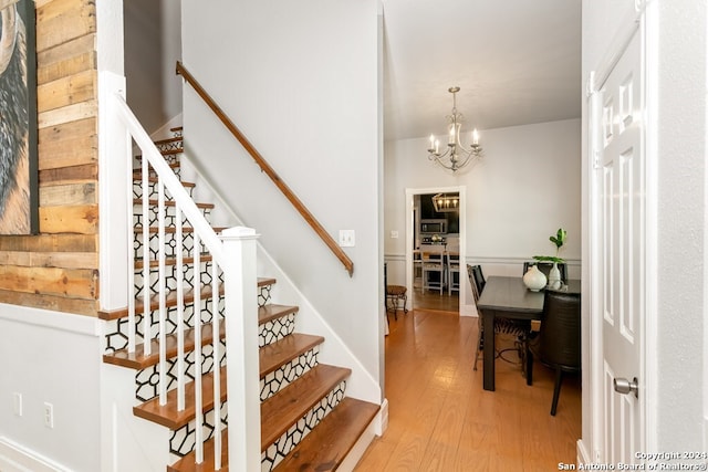 stairs featuring hardwood / wood-style floors and an inviting chandelier