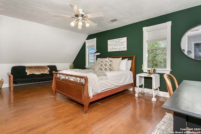 bedroom featuring a textured ceiling, ceiling fan, vaulted ceiling, and hardwood / wood-style flooring