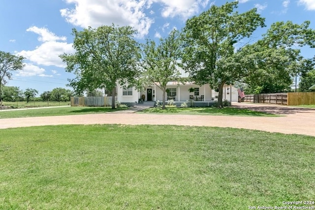 view of property hidden behind natural elements featuring a front lawn and a porch