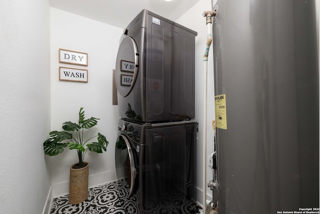 laundry area with water heater, stacked washer / dryer, and tile patterned floors