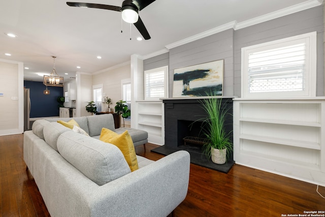 living room with ornamental molding, a brick fireplace, ceiling fan with notable chandelier, and dark hardwood / wood-style floors