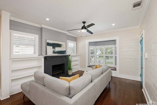 living room featuring ceiling fan, ornamental molding, dark hardwood / wood-style flooring, and a brick fireplace