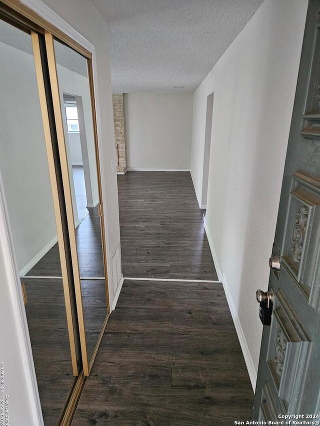 hallway featuring a textured ceiling and dark hardwood / wood-style floors