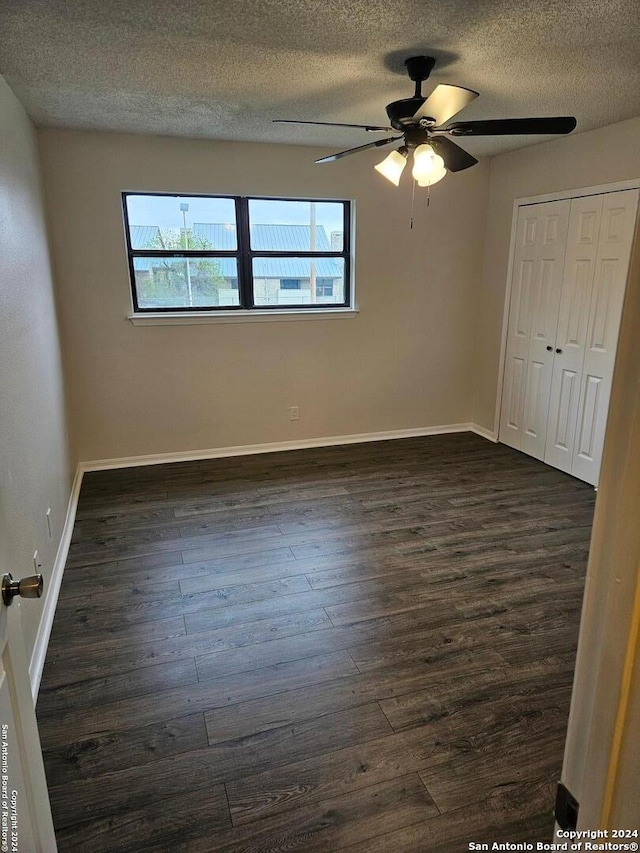 empty room featuring a textured ceiling, dark hardwood / wood-style floors, and ceiling fan