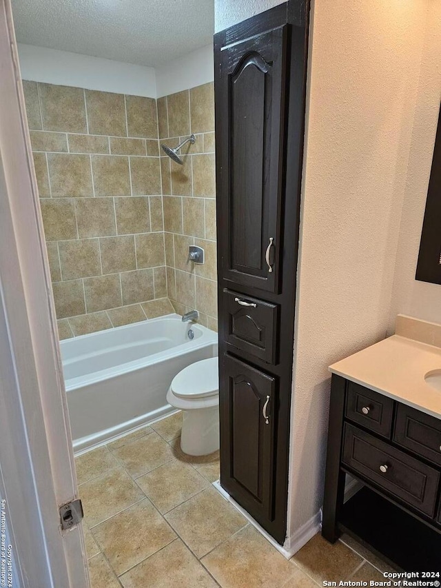 full bathroom with tile flooring, toilet, tiled shower / bath, vanity, and a textured ceiling