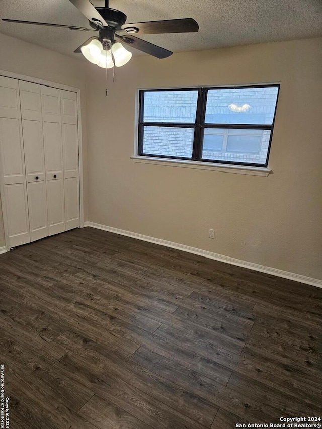 unfurnished bedroom featuring ceiling fan, a textured ceiling, dark hardwood / wood-style floors, and a closet