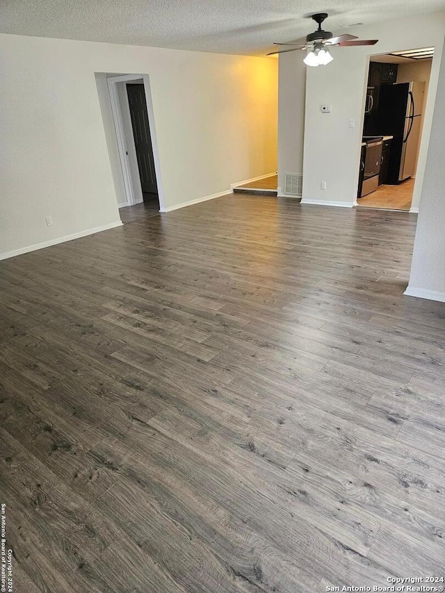 empty room featuring dark hardwood / wood-style flooring, a textured ceiling, and ceiling fan