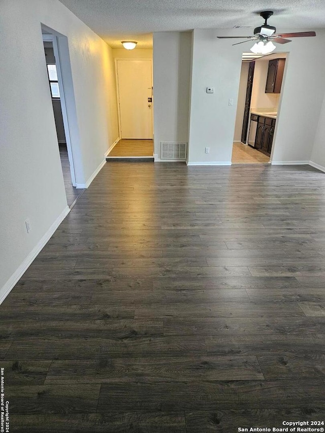 empty room with dark hardwood / wood-style flooring, ceiling fan, and a textured ceiling