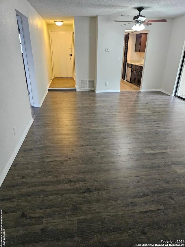 empty room with a textured ceiling, ceiling fan, and dark wood-type flooring