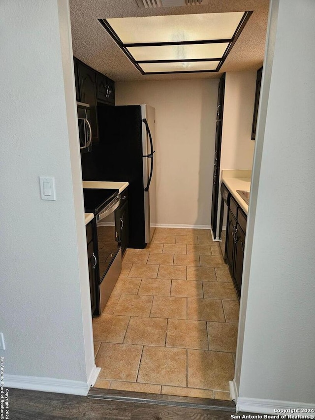 kitchen with a textured ceiling, light tile floors, and electric range