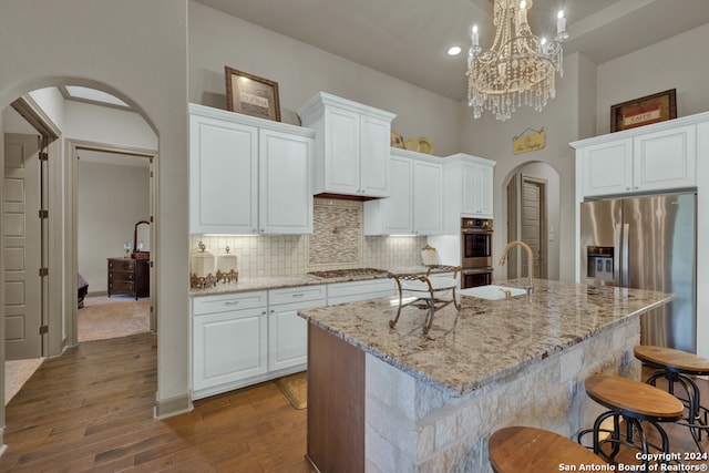 kitchen with a kitchen island with sink, a notable chandelier, and dark hardwood / wood-style floors