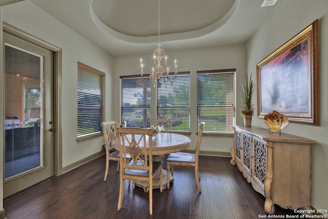 dining room featuring a chandelier, a raised ceiling, and dark hardwood / wood-style flooring