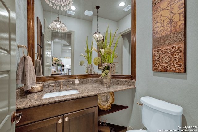 bathroom featuring an inviting chandelier, toilet, and vanity