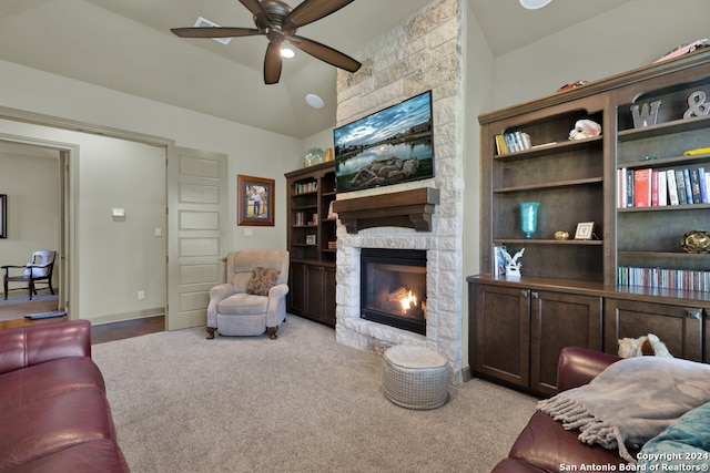 living room featuring a stone fireplace, ceiling fan, and light colored carpet