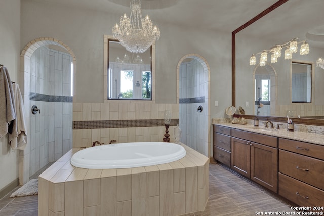 bathroom with shower with separate bathtub, a chandelier, oversized vanity, and a healthy amount of sunlight