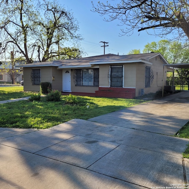 ranch-style house featuring a carport and a front lawn