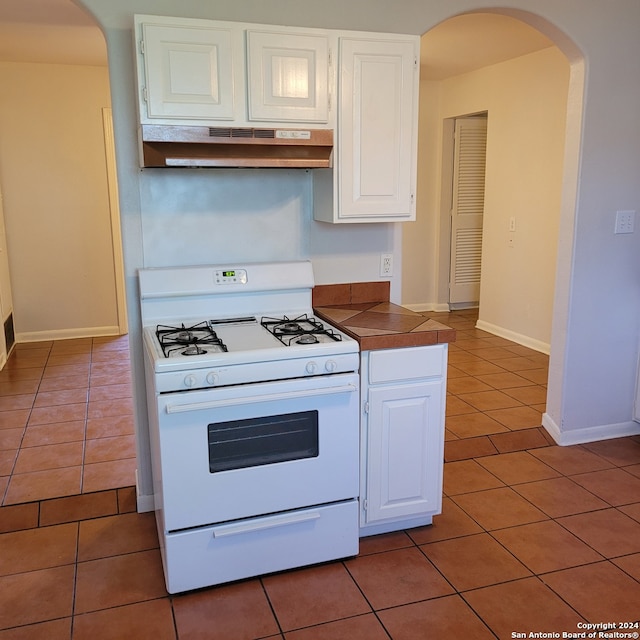 kitchen with white cabinets, tile floors, and white gas stove