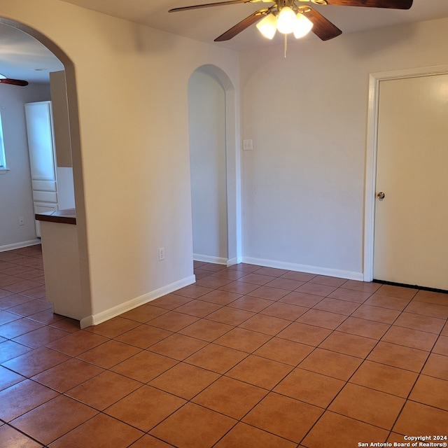 empty room featuring ceiling fan and dark tile flooring