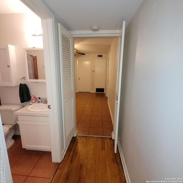 corridor with light wood-type flooring and sink