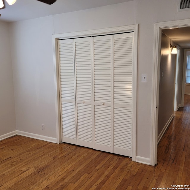 unfurnished bedroom with ceiling fan, dark hardwood / wood-style floors, and a closet