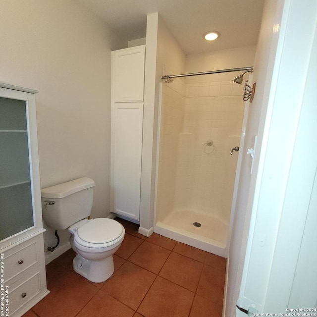 bathroom featuring toilet, tile flooring, and a tile shower