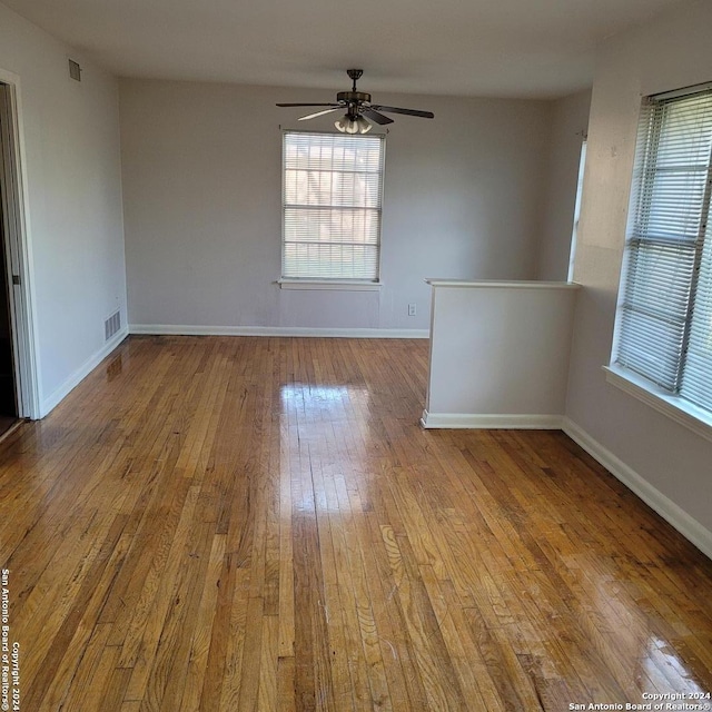 spare room featuring ceiling fan, a wealth of natural light, and hardwood / wood-style flooring