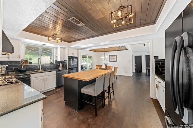 kitchen with tasteful backsplash, wood ceiling, a wealth of natural light, and black appliances