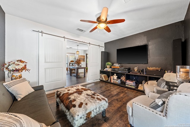 living room featuring a barn door, dark hardwood / wood-style flooring, and ceiling fan