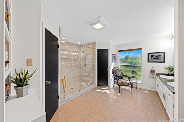 bathroom with a shower with shower door, tile flooring, and vanity