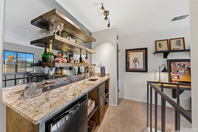 bar with stainless steel dishwasher, track lighting, sink, light stone countertops, and light carpet