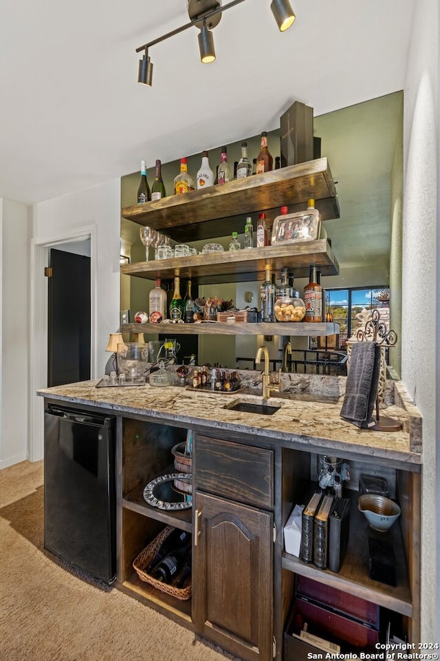 bar featuring light colored carpet, sink, light stone counters, black dishwasher, and dark brown cabinetry