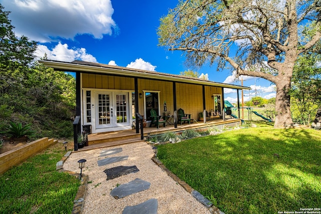 rear view of house with french doors, a yard, and a playground