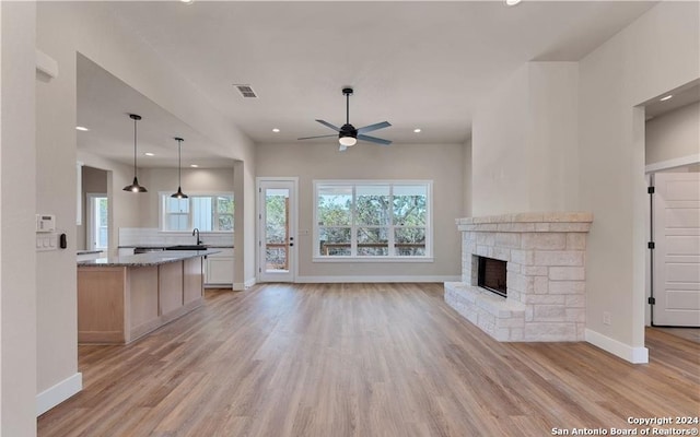 unfurnished living room with light hardwood / wood-style floors, sink, ceiling fan, and a fireplace